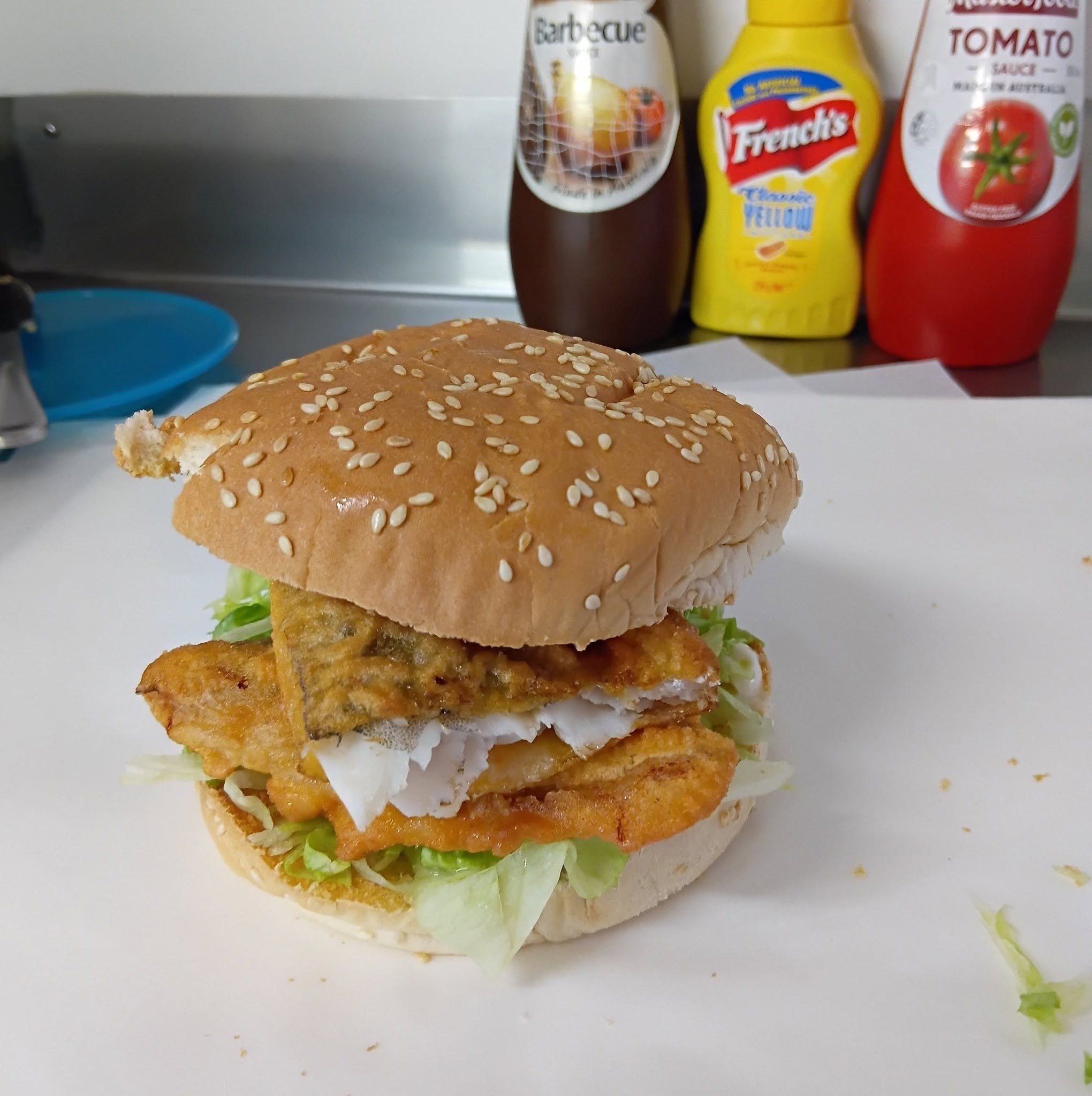 A golden battered fish burger with lettuce in a sesame seed bun